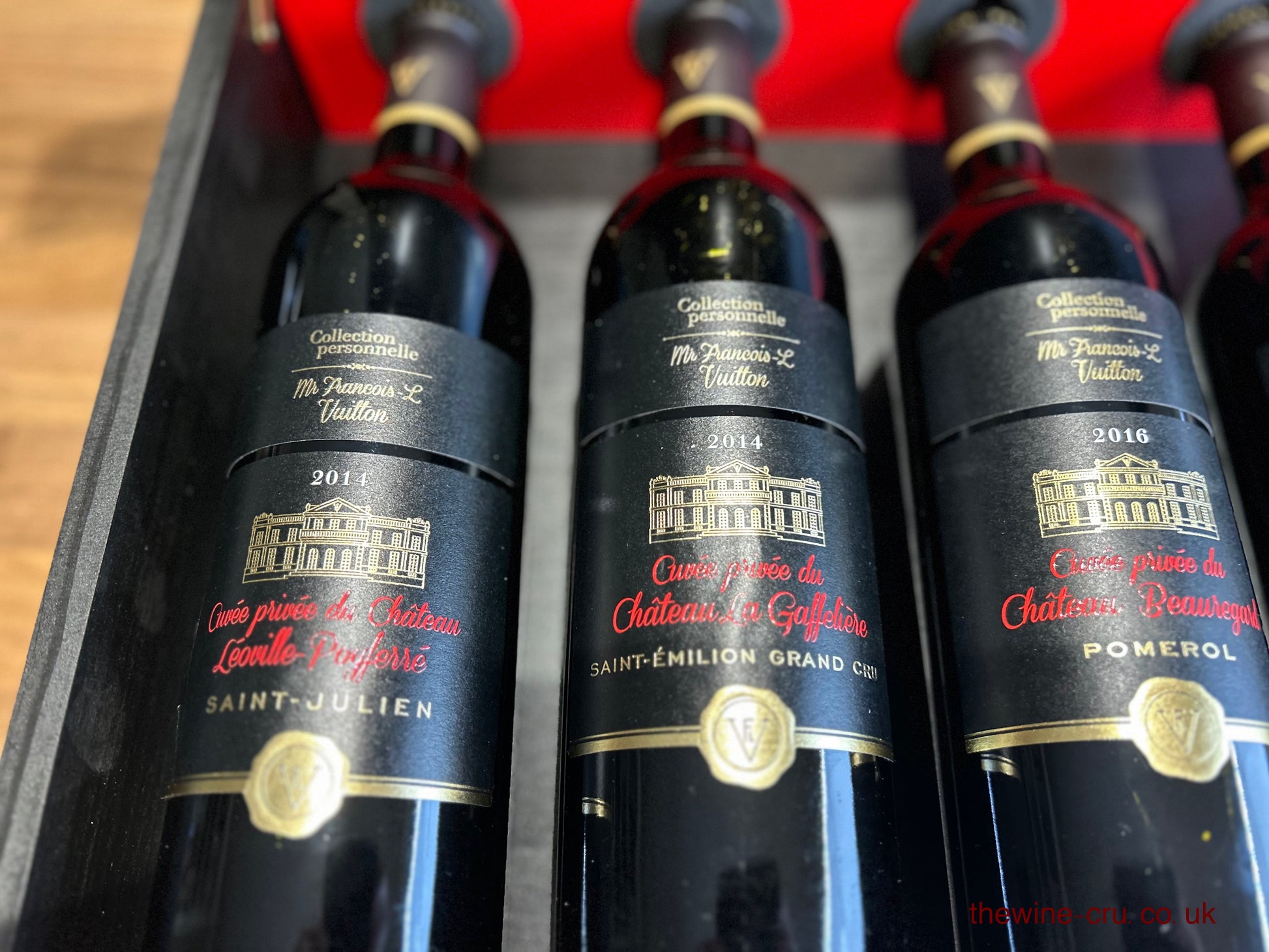 Close up of three of the six bottles in the branded wooden case