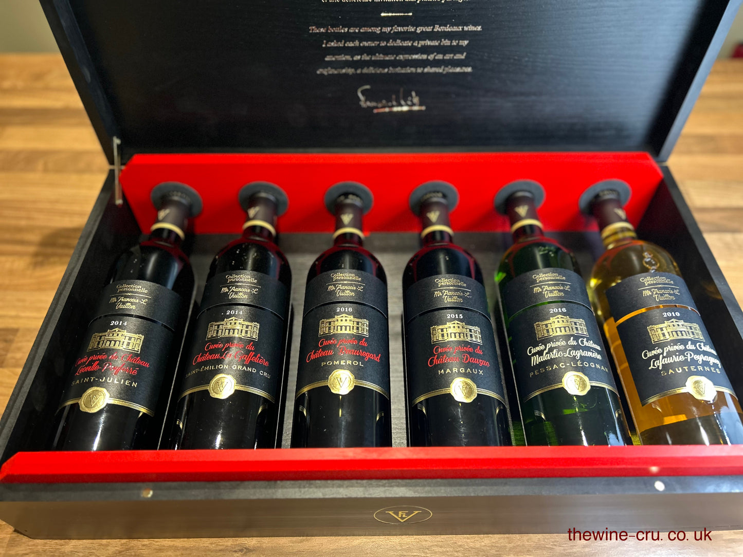 Set of wine bottles in a wooden box with visible branding.